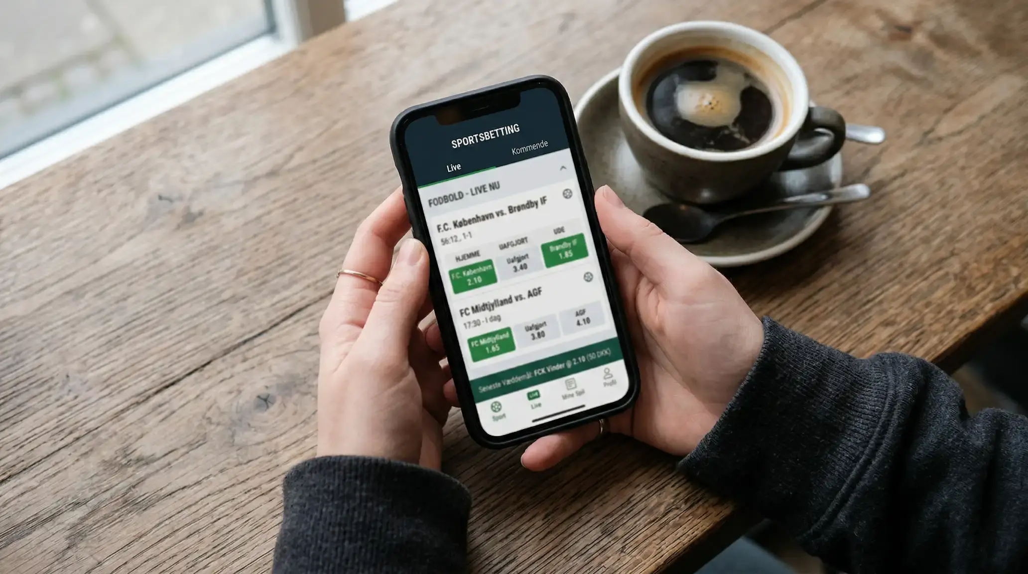 Dansk spiller bruger mobilen til fodbold betting med live odds på skærmen