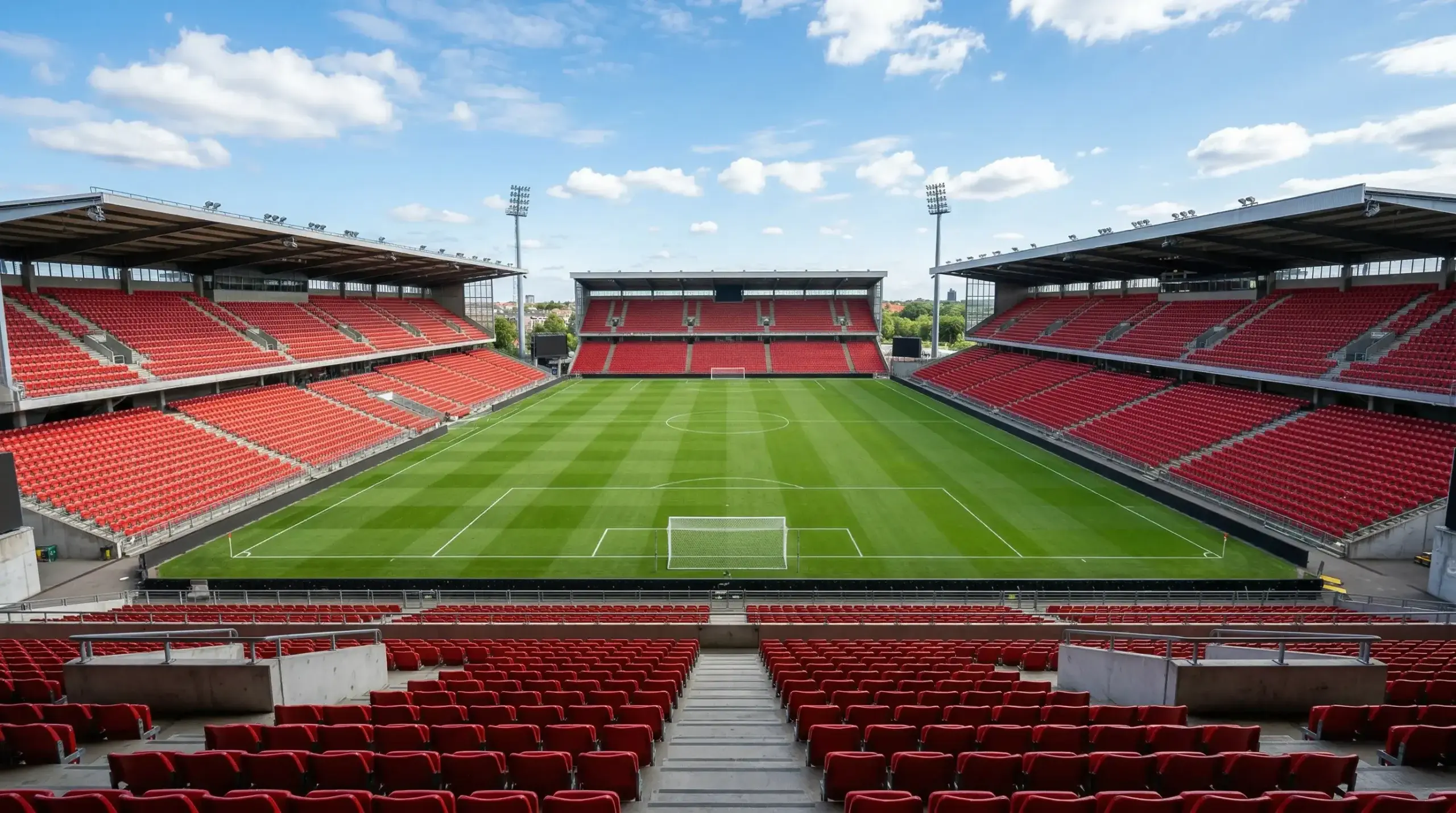 Dansk fodboldstadion med tribuner og grønt græs i dagslys