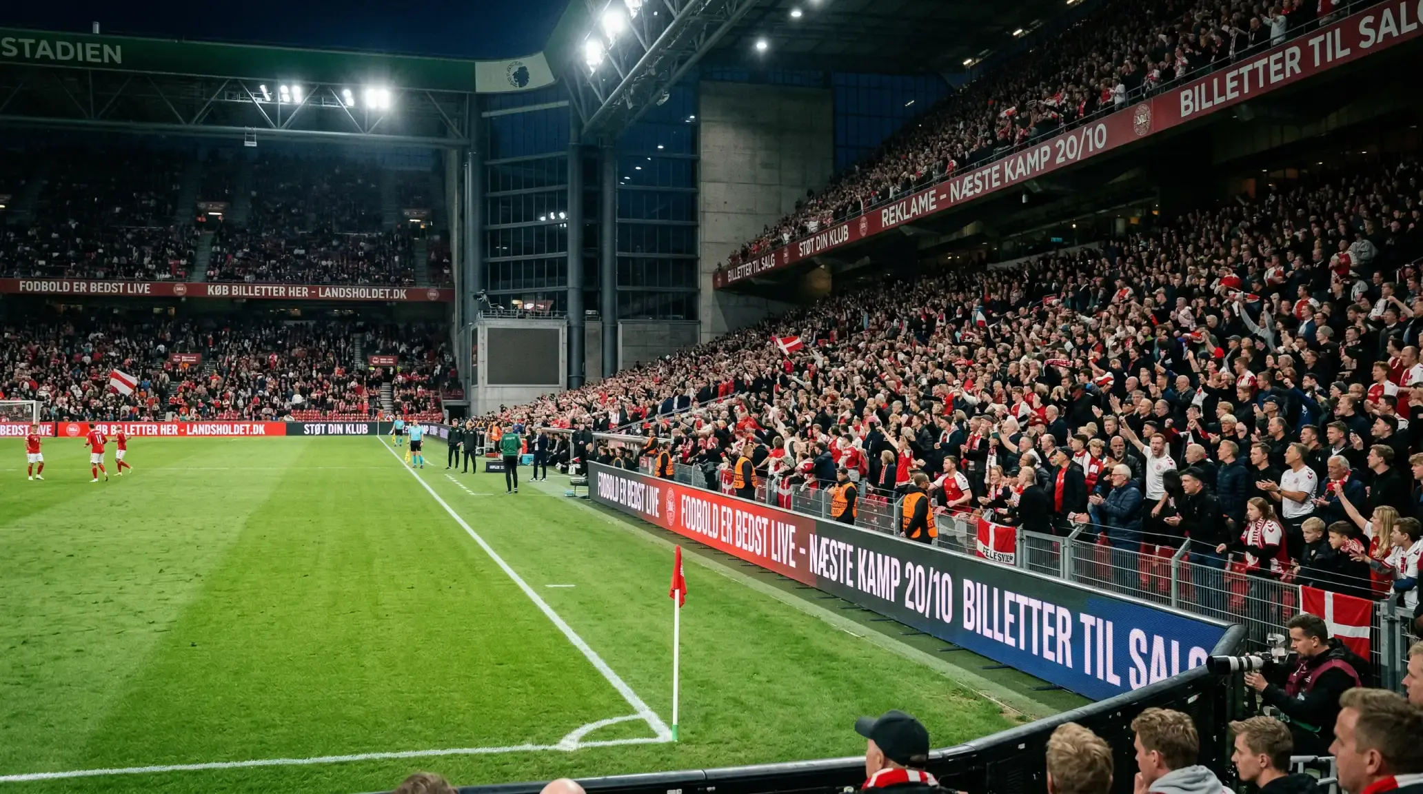 Fodboldbane med reklamebander langs sidelinjen under en aftenkamp